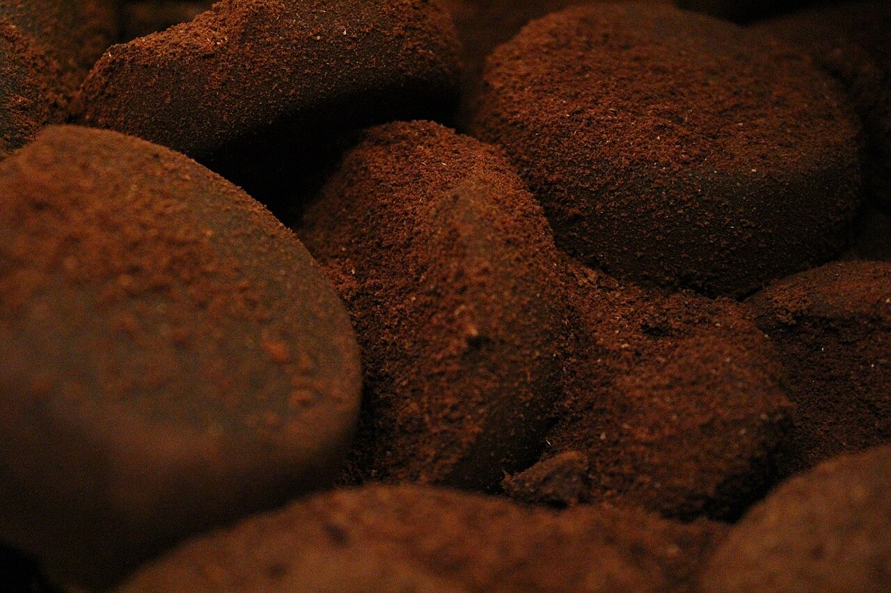 Close-up shot of rich, dark espresso flowing from a portafilter into a clear glass cup, showcasing thick, hazelnut-colored crema.