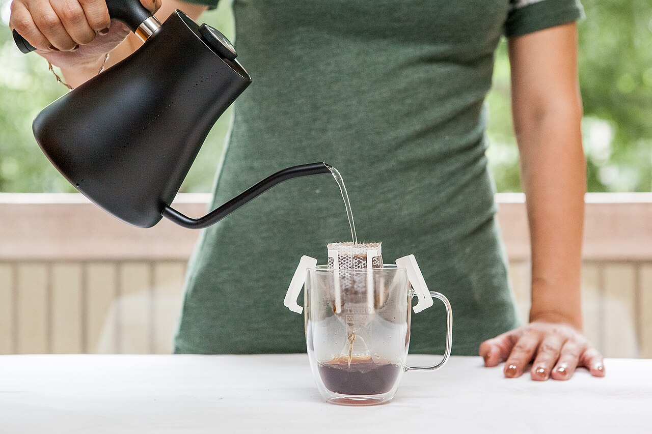 A barista meticulously pouring water over coffee grounds in a Hario V60 dripper, illustrating the precision of third wave brewing.